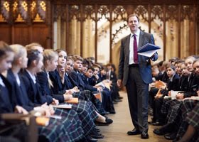 Headmaster standing in chapel with pupils sat on benches