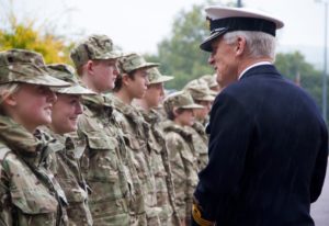 Line of CCF cadets with one girl smiling as army official speaks to her