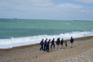 Senior pupils walking along the beach picking up rubbish