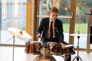 Senior school drummer playing in the New Bury Theatre foyer