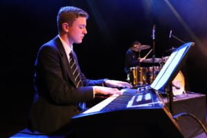 Senior boy playing the keyboard on stage under a spotlight