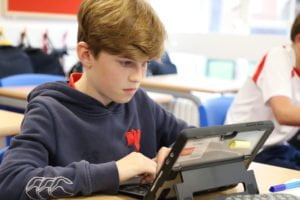 Boy in classroom working on a digital tablet