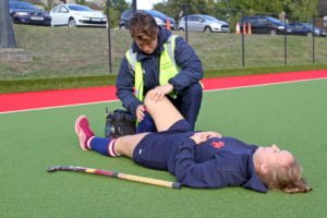 Girl lying in the floor with the physio pushing her knee to chest