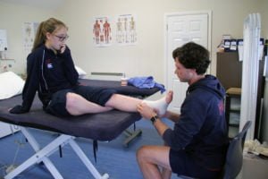 Girl on physio bed having her ankle assessed by the physio