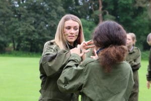 Girls in CCF Army uniform putting on face paint