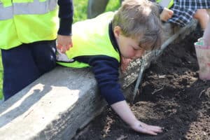 Young boy touching the soil in a flowerbed