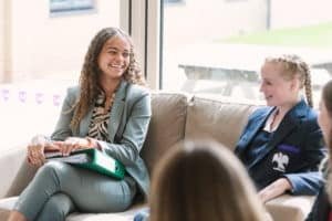 Lower sixth student sitting with younger pupil on sofa