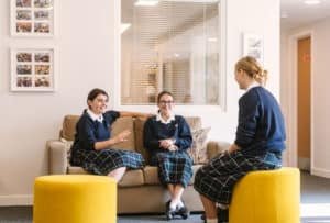 Three girls sitting on yellow furniture talking