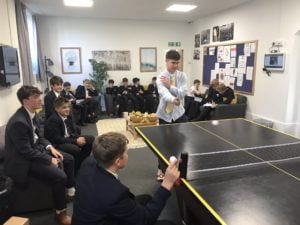 Boys gathered around a table tennis table as two boys play