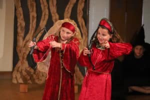 Two girls dressed in red with bows and arrows